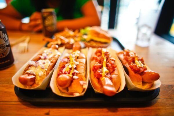 Close-up of various hotdogs with toppings on a wooden table, ideal for fast food themes.